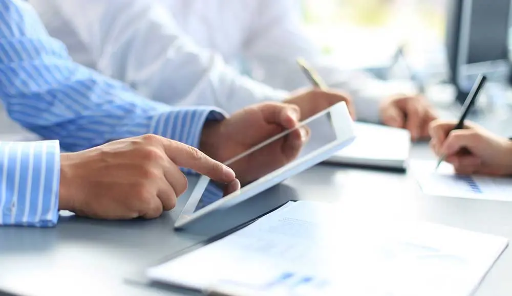Two people looking at a tablet with financial statements.