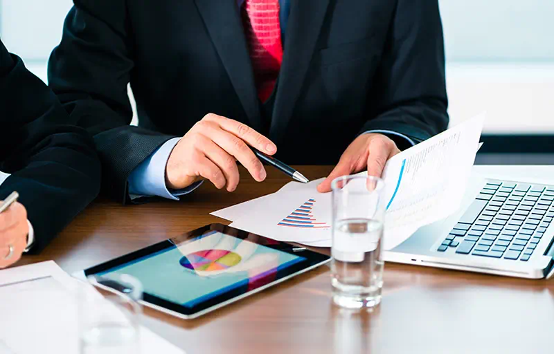 Two business men looking through a report with charts and graphs.