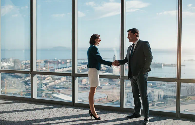 Lease Negotiation Two business people shaking hands in an empty office space.