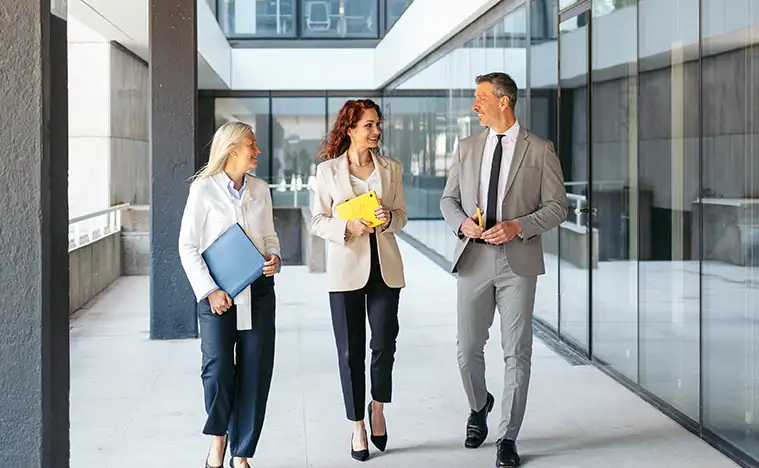 Business team walking and discussing work in office corridor.