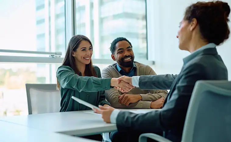 An agent shaking hands with two business owners