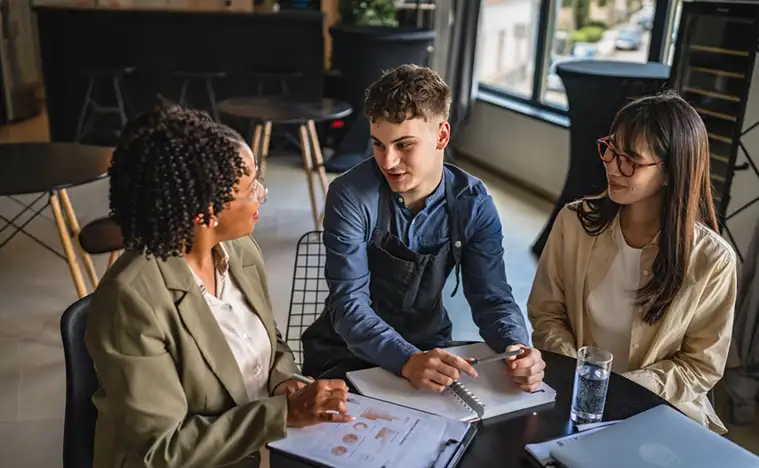 A business woman meets with coffee shop owners.