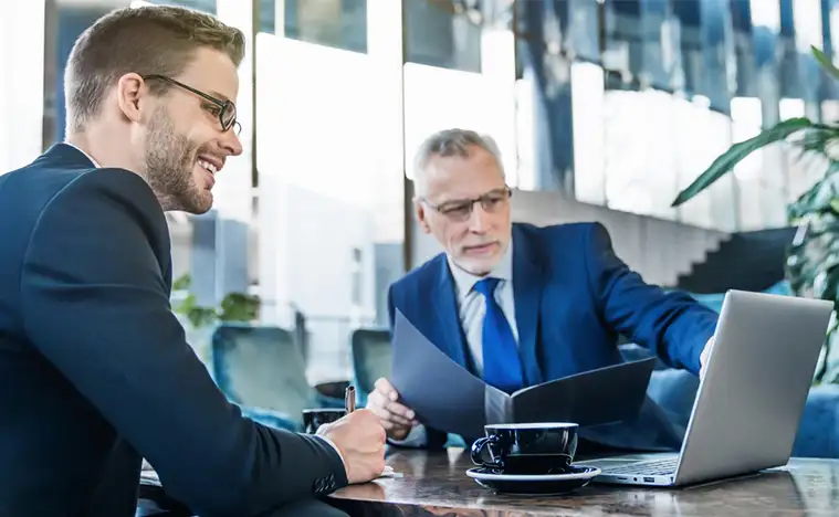 Two business men looking over reports on a laptop.